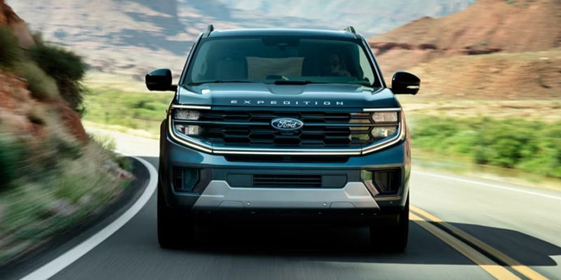 Blue Ford Expedition SUV driving on a winding mountain road.